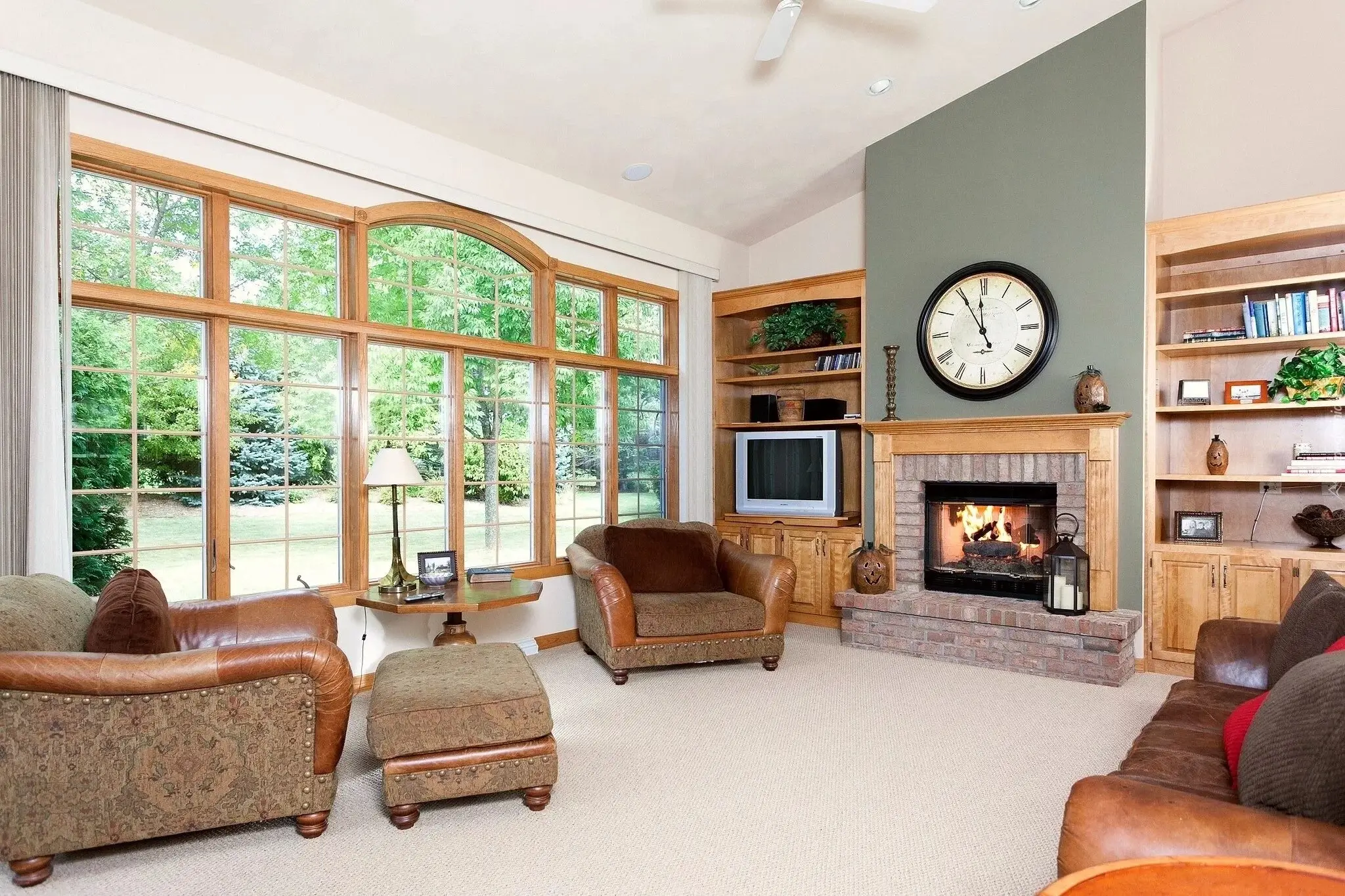 A large wooden clock above a fireplace in a cozy living room.